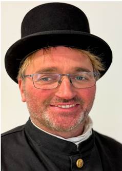 Ein Bild, das Kleidung, Kopfbedeckung, Menschliches Gesicht, Hut enthlt.

Automatisch generierte Beschreibung